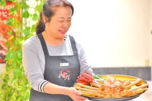 笑顔でカニを運ぶ女将